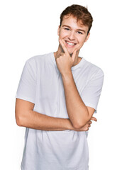 Fototapeta na wymiar Young caucasian man wearing casual white t shirt looking confident at the camera smiling with crossed arms and hand raised on chin. thinking positive.