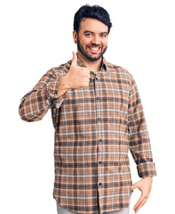 Young hispanic man wearing casual clothes doing happy thumbs up gesture with hand. approving expression looking at the camera showing success.