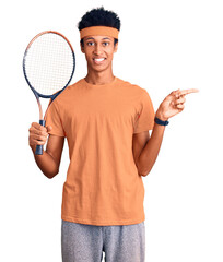 Young african american man playing tennis holding racket smiling happy pointing with hand and...