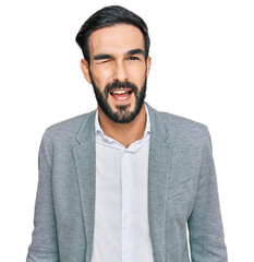 Young hispanic man wearing business clothes winking looking at the camera with sexy expression,...
