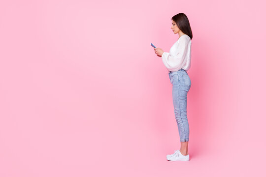 Profile full body photo of cute young lady hold telephone chatting friends clients dressed stylish outfit isolated on pink color background