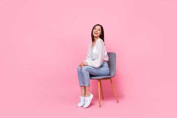 Full length photo of cute lovely lady sit armchair good mood dressed trendy clothes empty space isolated pink color background