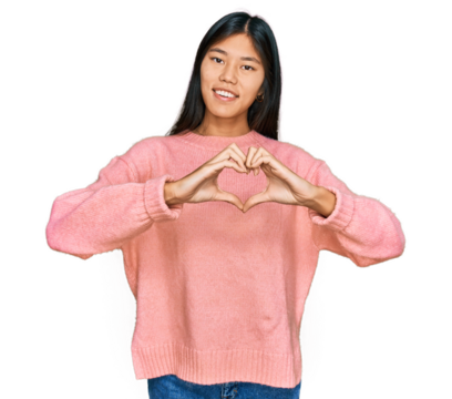Beautiful young asian woman wearing casual winter sweater smiling in love doing heart symbol shape with hands. romantic concept. - Powered by Adobe