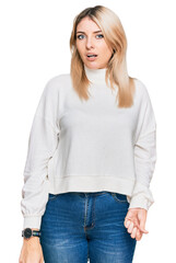 Obraz premium Young caucasian woman wearing casual winter sweater in shock face, looking skeptical and sarcastic, surprised with open mouth