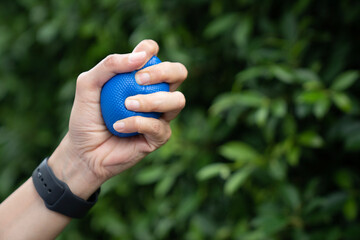 Hands of a woman squeezing a blue stress ball, close up