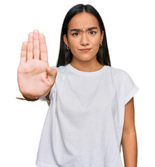 Young asian woman wearing casual white t shirt doing stop sing with palm of the hand. warning...
