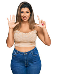 Beautiful brunette woman wearing casual clothes showing and pointing up with fingers number seven while smiling confident and happy.