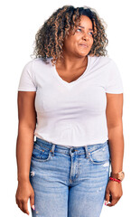 Young african american plus size woman wearing casual clothes smiling looking to the side and staring away thinking.