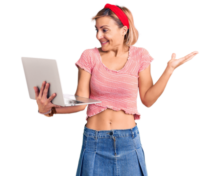 Young blonde woman holding laptop celebrating victory with happy smile and winner expression with raised hands
