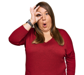 Beautiful brunette plus size woman wearing casual clothes doing ok gesture shocked with surprised face, eye looking through fingers. unbelieving expression.