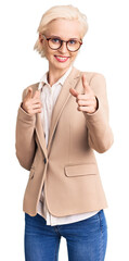 Young blonde woman wearing business clothes and glasses pointing fingers to camera with happy and...