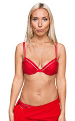 Fototapeta premium Young blonde woman wearing bikini with serious expression on face. simple and natural looking at the camera.