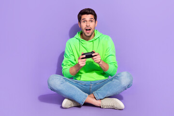 Full length photo of cheerful impressed guy dressed neon sweatshirt enjoying playstation isolated...
