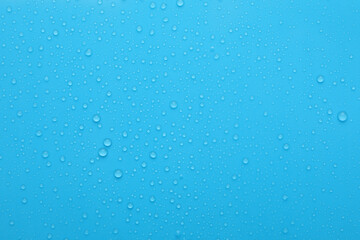 Water drops on light blue background, top view