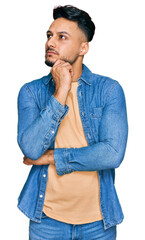 Young arab man wearing casual clothes serious face thinking about question with hand on chin,...