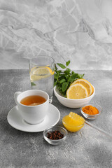 Cup with delicious immunity boosting tea and ingredients on grey table