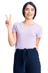 Obraz premium Brunette teenager girl wearing casual clothes showing and pointing up with fingers number two while smiling confident and happy.