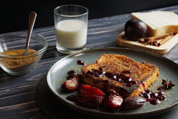 French toast with baked plums, served on a plate. Table top shot.