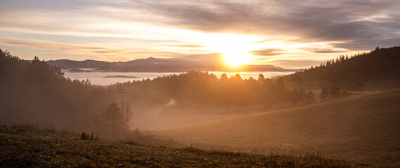 sunrise over a mountain below a misty valley
