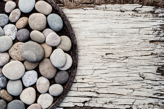 Rustic Contemplation. Still Life Photography. Stones on a rusted cylinder on an old board. 