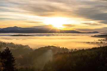 Fototapeta premium sunrise over a mountain below a misty valley 