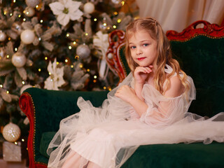 Little girl dreams near the Christmas tree at home dreams