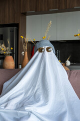 White ghost with black eyes, made from a bedsheet. whit hat