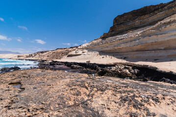 High and steep white rocky desert cliff and brown coastline surface with gaps with huge abyss in the middle, Canary Islands
