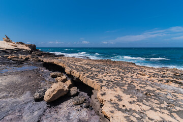 Brown rocky beach pavement plateau with many small gaps and Atlantic ocean in distance, Canary Islands 