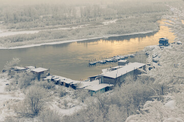 Obraz premium Winter landscape - view of the river bay and the boat station covered with snow
