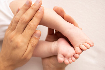 Children's foot in the hands of mother, father, parents. Feet of a tiny newborn close up. Little baby legs. Mom and her child. Happy family concept. Beautiful concept image of motherhood stock photo. 