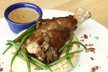 Cooked pork shank with mashed potatoes, gravy and green beans