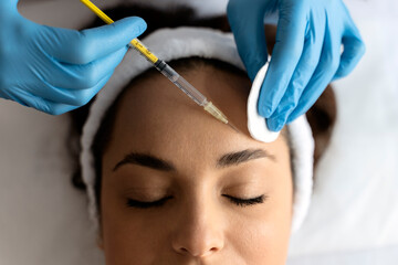 Young woman attending beautician, having anti-aging injection at her face