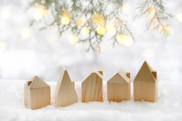 Happy New Year and Merry Christmas greeting card with Toy wooden houses, spruce branches on white snow background of a beautiful bokeh