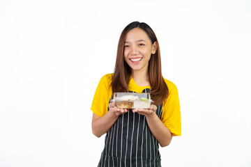 Holding Krapao (Thai food) box, Portrait of confident asian woman barista and food owner shop with yellow t-shirt and black apron standing on white background.