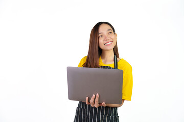 Obraz premium Using laptop, checking email or online order, Portrait of confident asian woman barista and food owner shop with yellow t-shirt and black apron standing on white background.