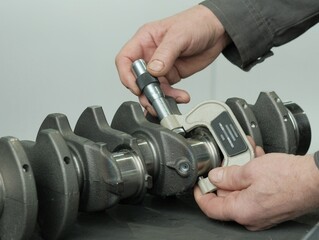 The mechanic measures the crankshaft neck. The mechanic uses a micrometer for control. The...