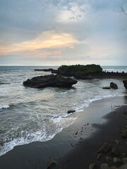 view of the coast with black sand and sunset over the ocean