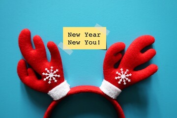 Red reindeer headband on blue background and a yellow sticky note written NEW YEAR NEW YOU ,...