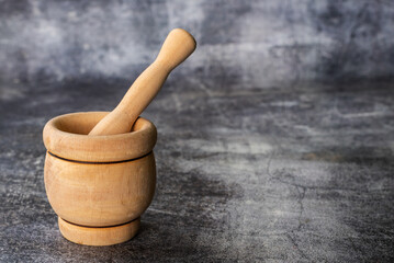 Wooden mortar,kitchen utensil for mash,on a gray stone background,close-up.