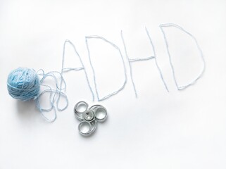 the inscription ADHD and a clew yarn on a white background. spinner helps children with ADHD,...