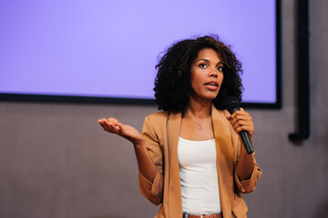 African businesswoman giving the lecture to the public, using and holding a microphone.