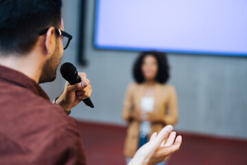 Businessman holding a microphone, asking the female presentator something.