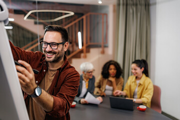 Cheerful businessman writing a business plan on a whiteboard,standing at the office.