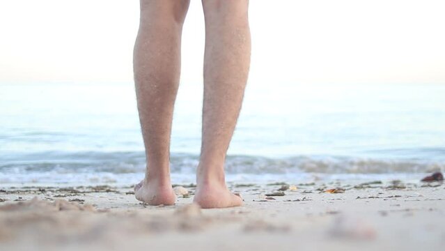 Barefoot male legs stand on the wet coastal sand on the shores of Puerto Progreso yucatan, mexico