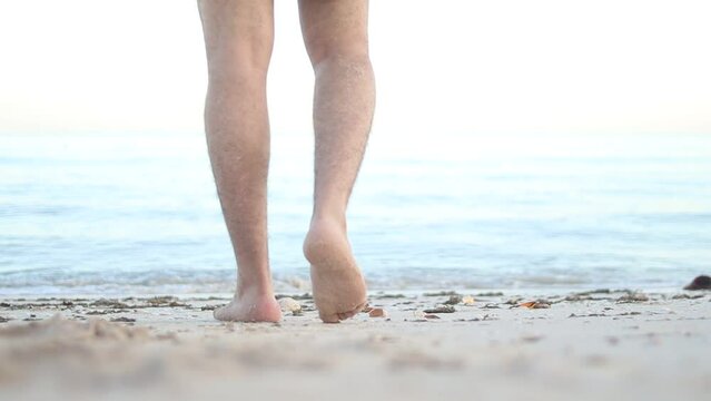 Barefoot male legs stand on the wet coastal sand on the shores of Puerto Progreso yucatan, mexico