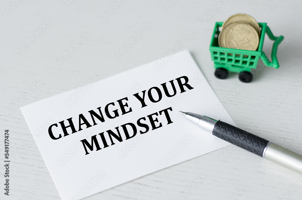 Poster change your mindset text on a card on a table next to a pen and coins in a basket