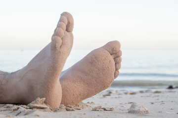 Barefoot male legs stand on the wet coastal sand on the shores of Puerto Progreso yucatan, mexico