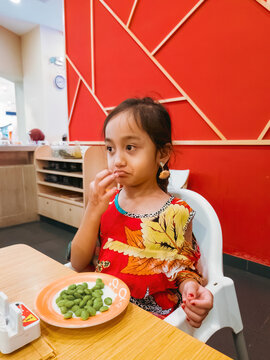 Child Is Unhappy Eating Edamame Beans At Sushi Restaurant, Malaysia.