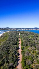 Vertical aerial view of a road surrounded by green nature near the North Shore beach, Australia
